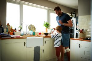 Little boy helping his father to make breakfast in kitchen